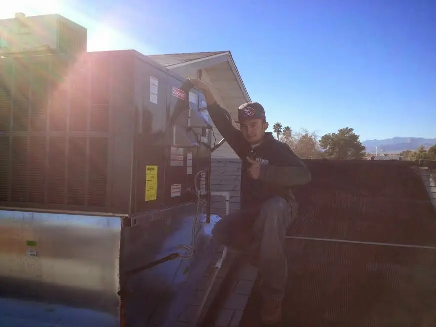 HVAC technician performing Air Duct Repair on a rooftop unit in Norwood